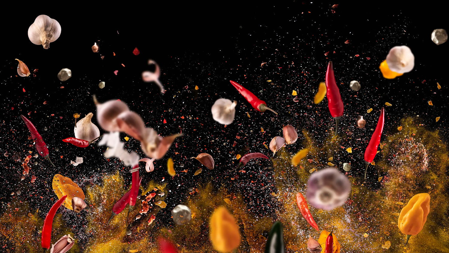 Red peppers, garlic, and spices flying through the air with a black background